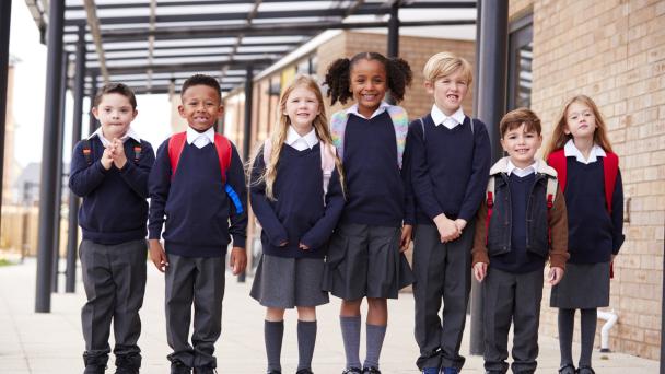 Primary school children standing in a line, smiling.